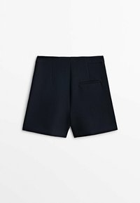 Shorts noirs sur mesure avec une coupe droite, une taille haute et une seule poche passepoilée sur le côté arrière droit.