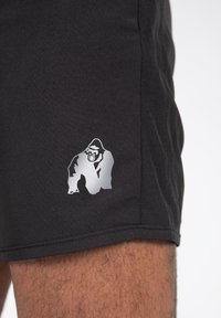 Crne atletske kratke hlače s teksturiranim finišom, s srebrnim logotipom gorile na donjoj strani. Jednostavan dizajn s ravnim krojem.