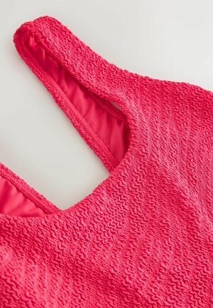 Texturált rózsaszín fürdőruha tank top stílusban, redős külsővel és sima belső béléssel. Állítható pántok a tökéletes illeszkedésért.