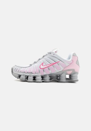 Sapatilha atlética Nike em branco e rosa claro. Possui um upper em malha e uma sola curva distinta com amortecimento de ar visível.