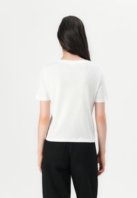 White short-sleeve t-shirt with a round neck, made of soft cotton. The back features a clean design and a slightly cropped cut.