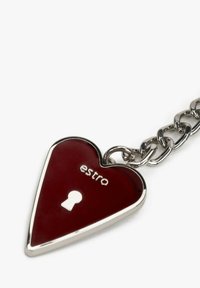 Breloczek w kształcie serca w ciemnoczerwonym emaliowanym wykończeniu, z srebrnym sprzętem, z wzorem naśladującym zamek i wypukłym napisem "estro" na przodzie.