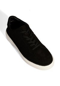 Baskets en suede noir avec semelle en caoutchouc blanche, bout rond et design à lacets. Présente des coutures discrètes et un dessus texturé.