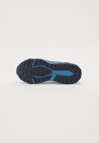 Suela de zapatilla en azul y gris oscuro con un patrón de goma texturizada. Incluye un acento azul en el centro y un logotipo grabado en el lado.