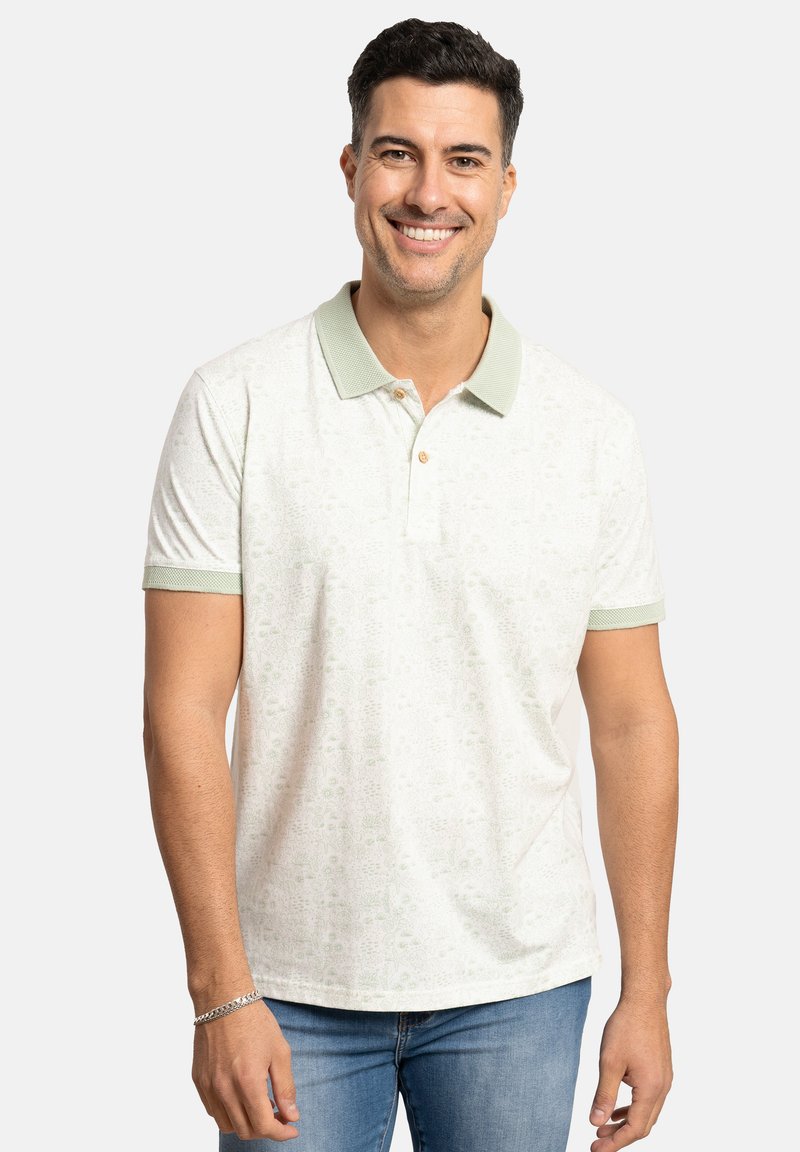 Camisa polo en blanco con sutiles patrones verdes, con un cuello verde claro y tapeta de dos botones. La tela parece suave y lisa.