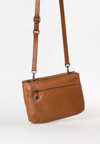 Braune Leder-Crossbody-Tasche mit Reißverschluss, verstellbarem Tragegurt und einer vorderen Reißverschlusstasche. Glatte Textur mit kontrastierenden Nähdetails.