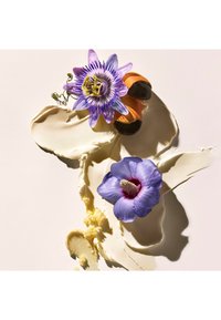 Kremet beige tekstur med bølger, toppet med en lilla pasjonsblomst og en blå hibiskus, begge med detaljerte kronblader og kontrasterende farger.