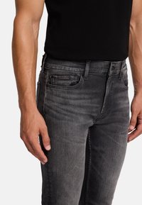 Dunkelgraue Denim-Jeans im Slim-Fit-Stil, mit traditionellem Fünf-Taschen-Design und subtilen Verblasungen. Das Material ist weich und hat eine glatte Textur.