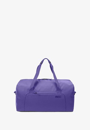 Sac de sport violet avec extérieur en tissu, double poignées et compartiment principal zippé. Comprend une petite poche avant et un logo embossé.