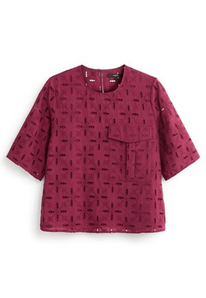 Bordeauxrode blouse met korte mouwen, ronde uitsnijdingspatronen, een voorvak met klep, ronde halslijn en een rits aan de achterkant.
