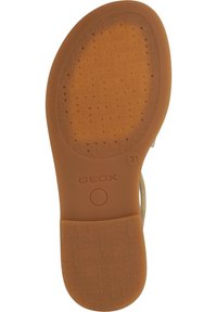 Brun gummisul med texturerad yta och perforeringar. "GEOX"-logotyp präglad över hela ytan med ett cirkulärt emblem nära hälen.