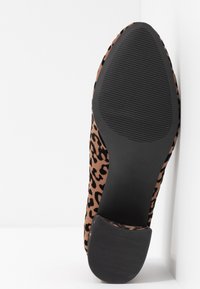 Leopard print flat shoe featuring a soft, suede-like texture, a black rubber sole with grooves, and a rounded heel for stability.
