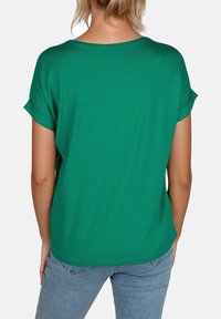 Camiseta verde de manga corta y cuello redondo, hecha de fabric suave, con mangas enrolladas y un corte relajado. Presenta un dobladillo recto.