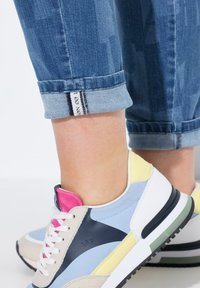 Tenisky s kombinací světle modré, růžové, žluté a béžové materiály a masivní podrážkou. Otočený denimový manžeta se pruhovanou nášivkou.