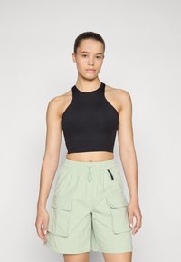 Must mustakangas crop top mustana, mis on koos heledate roheliste cargo-shortsidega, millel on elastne vöökoht ja kaks küljetaskut. Sile tekstuur, juhuslik disain.