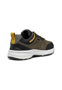 Zapatilla chunky en verde oliva y negro con acentos amarillos. Presenta un upper texturizado, cuello acolchado y suela de goma blanca con un patrón de agarre.