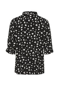 Schwarze Bluse mit einem gepunkteten weißen Muster, klassischem Kragen und drei Viertelärmeln mit Rüsche an den Bündchen. Glatte Stofftextur.