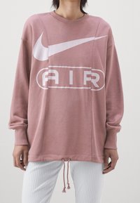 Růžová oversized mikina s kulatým výstřihem, s bílým logem Nike a potiskem "AIR", s tkaničkovým lemem a vroubkovanými manžetami.