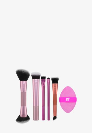 Seks lyserøde og lilla makeup-redskaber, herunder fem børster i forskellige størrelser og en lyserød blending-svamp med strop.