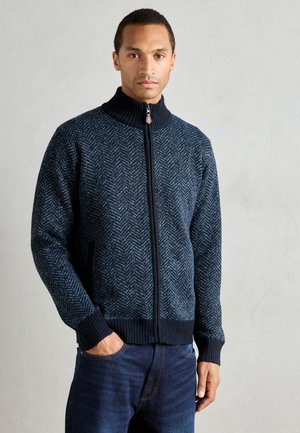 Marine zip-up trui met visgraatpatroon, hoge kraag en geribbelde manchetten. Gemaakt van textuur gebreide stof met contrasterende donkere accenten.