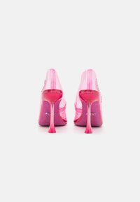 Chaussures à talons hauts transparentes de couleur rose clair avec un dessus transparent et une plateforme pailletée rose. Présentent un bout pointu et des talons aiguilles fins et transparents.