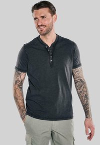Dark gray cotton henley shirt with short sleeves, five-button placket, and a ribbed collar. Features visible stitching and relaxed fit.