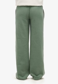 Grüne, weite Sweatpants aus einem weichen Baumwollmix; verfügen über Seitentaschen und einen elastischen Bund für zusätzlichen Komfort. Keine sichtbaren Muster oder Akzente.