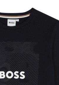 Zwarte katoenen t-shirt met een textuur grafiek van het merk "BOSS" in het wit, met een ronde hals en subtiele gestreepte details in de halslijn.