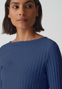 Navy blue ribbed top with a wide neckline, featuring a smooth texture and fitted silhouette, cut to the mid-bust area.