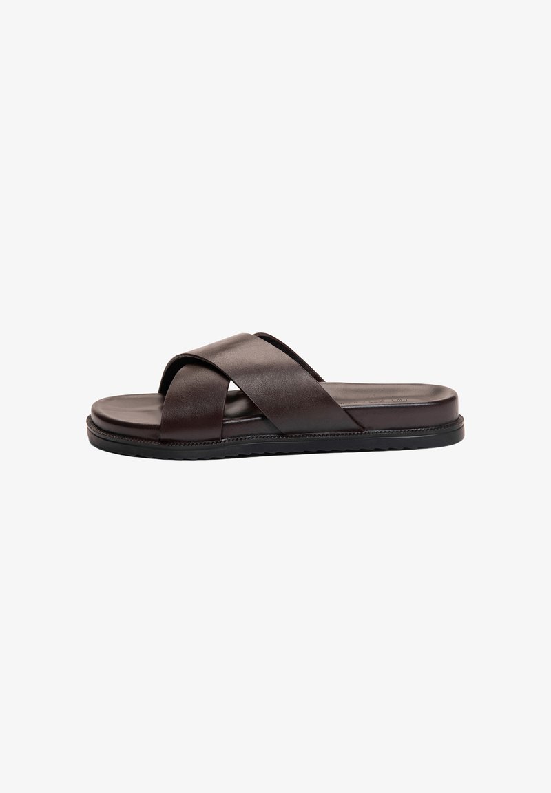 Sandale slide en cuir marron foncé avec larges brides croisées et semelle plate en caoutchouc noir.