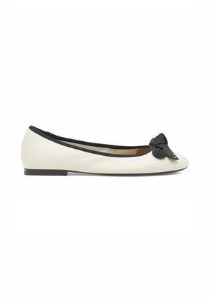 Bailarina de cuero blanco con ribete negro, suela plana y lazo decorativo negro en la punta.