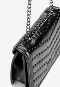 Borsa a mano in pelle nera con superficie testurizzata e borchie in rilievo. Presenta una tracolla a catena argentata e una forma strutturata.