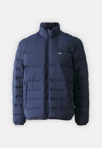 Marineblauwe donzen jas met een hoge kraag, rits aan de voorkant en een horizontaal doorgestikt patroon. Voorzien van een zijzak en een logodetail op de borst.