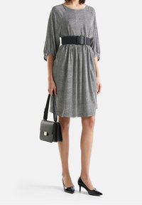 Černo-bílá šaty s puntíky, s nafouknutými rukávy, opásaným pasem a skládáním na sukni. Doplněno černými špičatými podpatky a malou kabelkou.