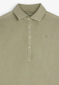 Světle khaki polo tričko vyrobené z texturované tkaniny. Obsahuje klasický límec, pět tlačítek na légu a malé vyšívané logo.