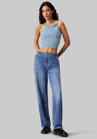 Top corto de mezclilla azul con un diseño de corte recto, combinado con unos pantalones vaqueros de pierna ancha en azul deslavado. Ambos presentan costuras visibles y un ajuste casual.
