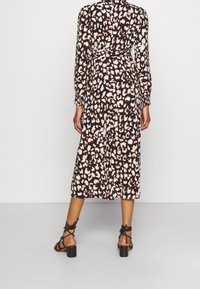 Svart midi-klänning med rosa och krämfärgad leopardprick. Har långa ärmar, en åtdragen midja och en flödande kjol. Bärs med svarta blockklacksandaler.