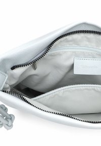 Balta ādas soma ar rāvējslēdzēja aizdari. Iekšpusē gaiša auduma oderējums, viena kabata ar rāvējslēdzēju un logotipa birka. Akcenti ietver melnas rāvējslēdzēja zobus.