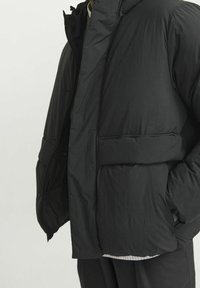 Gepolsterte schwarze Jacke mit hohem Kragen, Frontreißverschluss und Seitentaschen. Verfügt über eine glatte Textur und eine kastige Silhouette.