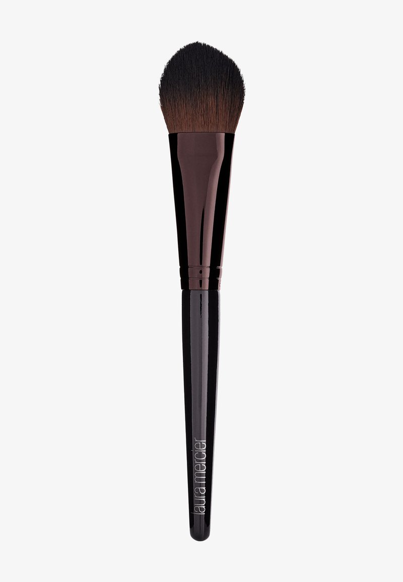 Rund, syntetisk makeupborste med ett mjukt, avsmalnande svart borsthuvud, glansig svart handtag och präglad logotyp nära basen.