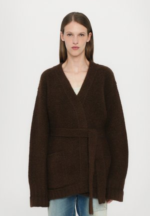 Brown, textured cardigan with a wrap design, long sleeves, and a tie belt. Features two front pockets and a relaxed fit.