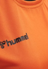 Orange atletisk trøje med rund hals, der har en struktureret stof og et sort "hummel" logo nederst til venstre.
