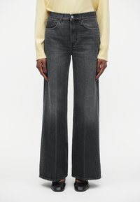 Hlače z visokim pasom in širokimi nogavicami iz temno sivega denima, z sprednjimi žepi, kontrastnim šivanjem in nekoliko zbledelim izgledom.