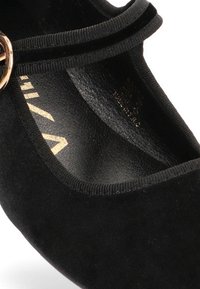 Zapato de tacón de ante negro con puntera redonda, que cuenta con una delgada correa para el tobillo y detalles en tono dorado. El forro interior suave mejora la comodidad.