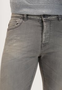 Jeans in denim grigio chiaro con un design elegante, stile classico a cinque tasche e un leggero effetto di whiskering sul tessuto per una maggiore texture.