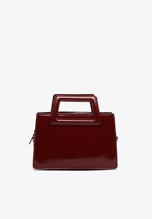 Ciemnoczerwona błyszcząca prostokątna torebka z geometryczną rączką i widocznym bocznym zamkiem na białym tle.