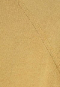 Tessuto di cotone giallo con una texture liscia, caratterizzato da cuciture diagonali e dettagli di cucitura sottili.