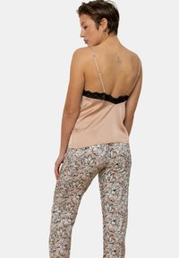 Camisole en satin rose doux avec bordure en dentelle noire ; associé à un pantalon à motifs avec des fleurs en rose et noir.
