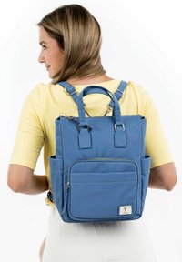 Blue fabric backpack with multiple pockets, a zipper closure, and dual top handles. Adjustable straps with silver hardware. Textured surface.