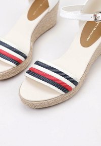 Sandali wedge bianchi con suola in juta intrecciata, dotati di una fascia in tessuto con righe blu, bianche e rosse, e una fascetta alla caviglia regolabile.